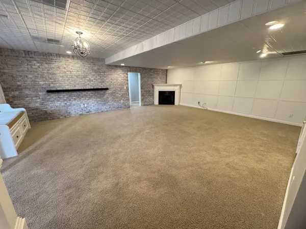 an empty room with windows and chandelier fan
