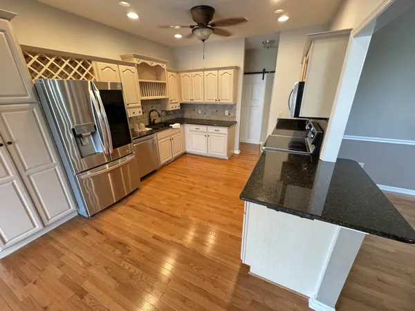 a kitchen with granite countertop a refrigerator and microwave