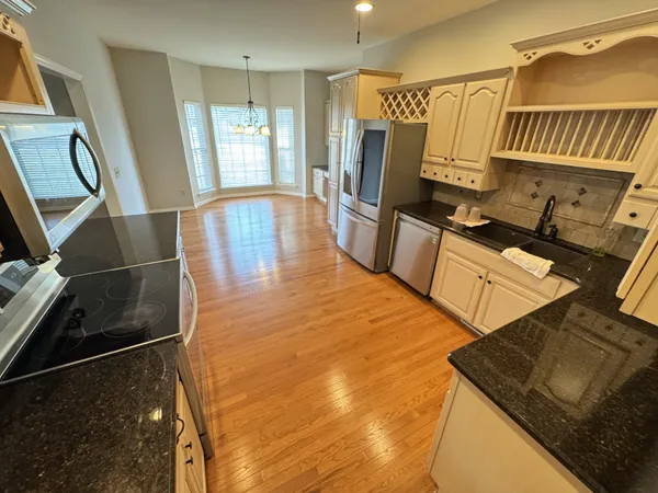 a view of a kitchen with fridge and wooden floor