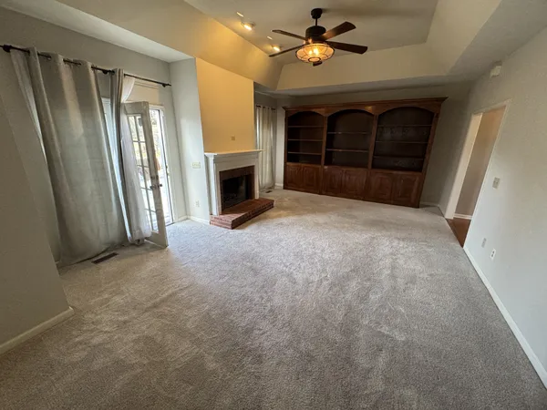 an empty room with fireplace cabinet and windows