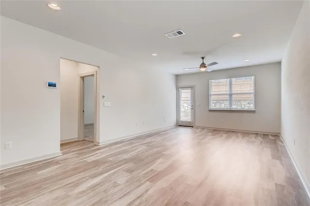 an empty room with wooden floor cabinet and windows
