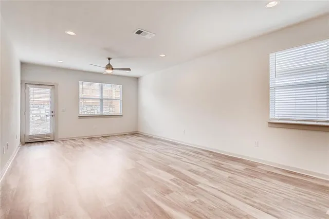 an empty room with wooden floor and windows