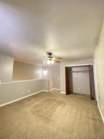 an empty room with closet and a ceiling fan