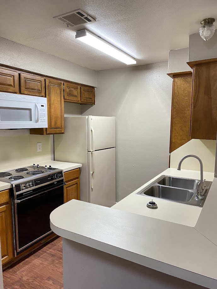 1305 West Villa Maria Road, Unit B107 Bryan, TX 77801 - Photo 7 of 17 a kitchen with a sink a stove and refrigerator