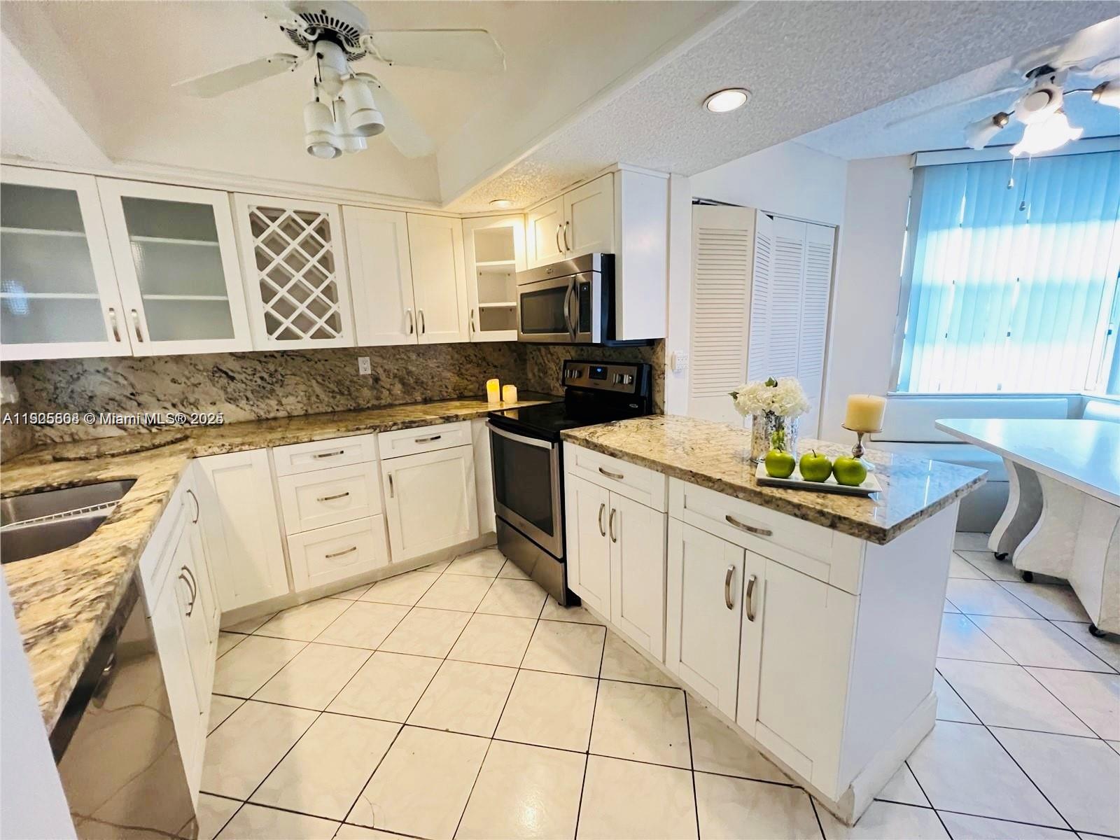 1830 Sabal Palm Drive, Unit 406 Davie, FL 33324 - Photo 3 of 16 a kitchen with granite countertop a sink a counter top space appliances and cabinets