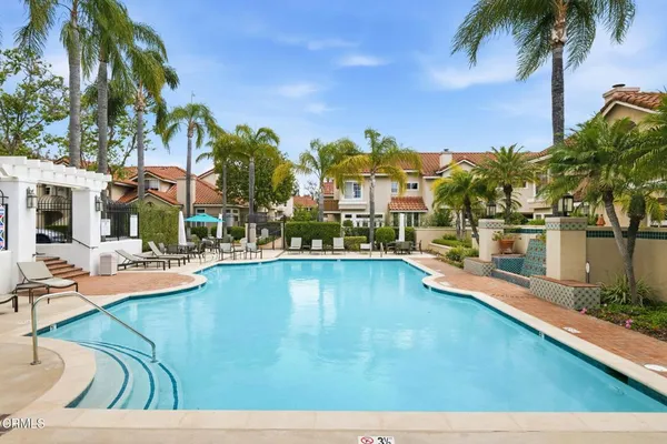 a view of a swimming pool with a lawn chairs under palm trees