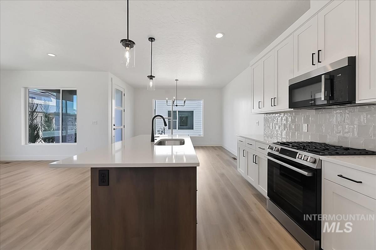 776 South Calhoun Lane Star, ID 83669 - Photo 9 of 49 Kitchen featuring a central island with a sink, white perimeter cabinetry, light-toned wood-finish flooring, and stainless steel appliances