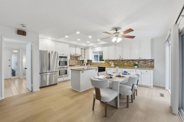 a kitchen with a refrigerator a sink dishwasher a dining table and chairs with wooden floor