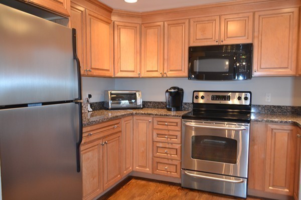 102 Jericho Road, Unit 102 Weston, MA 02493 - Photo 2 of 9 a kitchen with stainless steel appliances granite countertop white cabinets a microwave a sink and a refrigerator