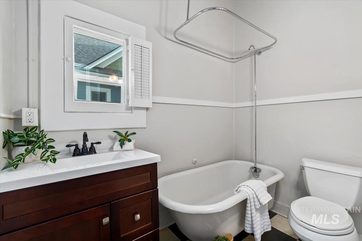 910 North 16th Street Boise, ID 83702 - Photo 23 of 47 Bathroom featuring a classic clawfoot tub with shower attachment, a dark wood-finish vanity with a white countertop, and a window with white louvered shutters