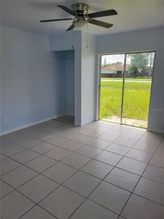 an empty room with a ceiling fan and a large window