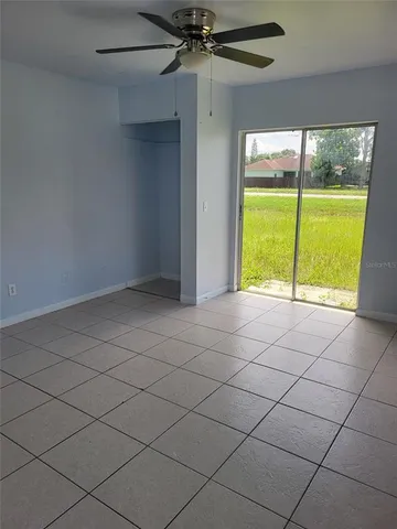 an empty room with a ceiling fan and a large window