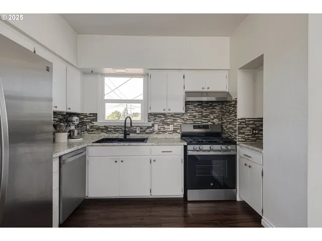 a kitchen with stainless steel appliances granite countertop a stove a sink and a refrigerator