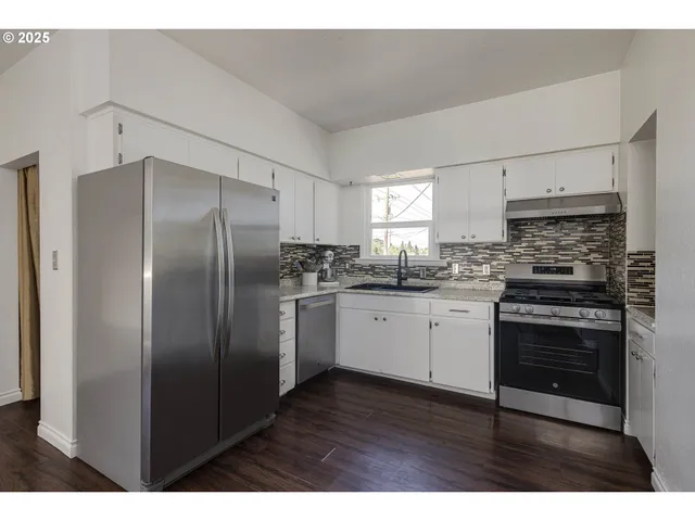 a kitchen with stainless steel appliances kitchen island granite countertop a refrigerator stove and sink