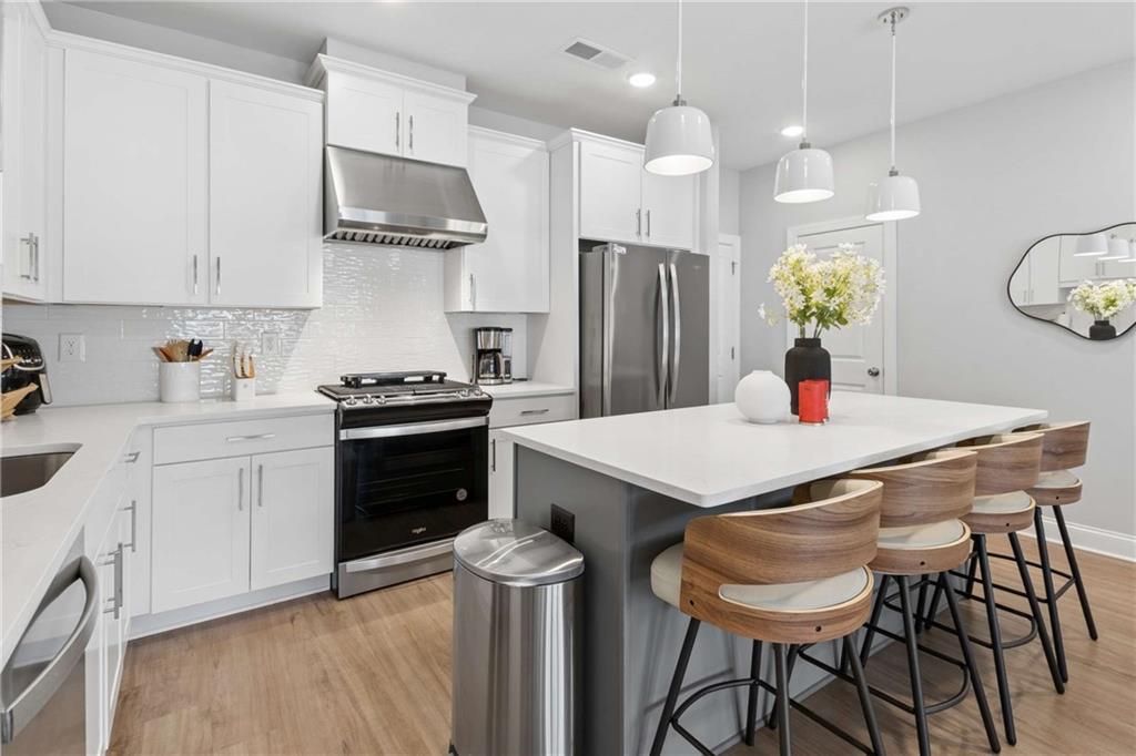 1324 Parc Bench Road Atlanta, GA 30316 - Photo 13 of 35 a kitchen with stainless steel appliances a stove a refrigerator a sink a dining table and chairs with wooden floor
