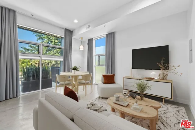 a living room with furniture a flat screen tv and a floor to ceiling window