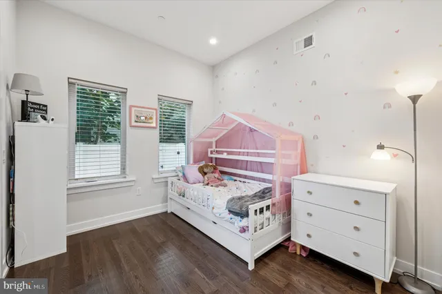 a spacious bedroom with a bed and wooden floor