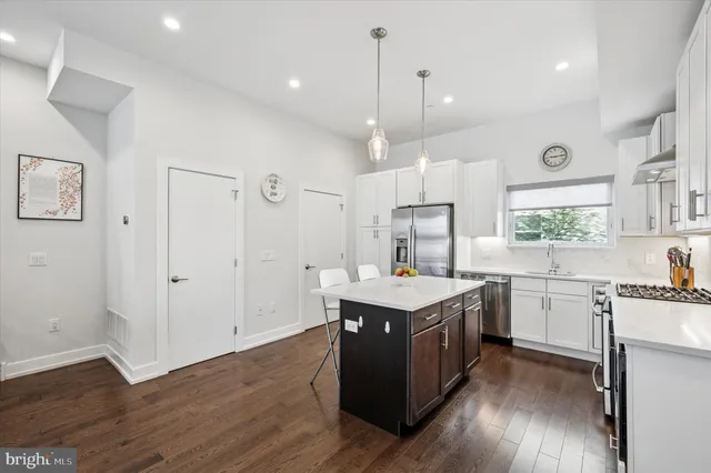 a kitchen with granite countertop a stove a sink dishwasher and a refrigerator with wooden floor