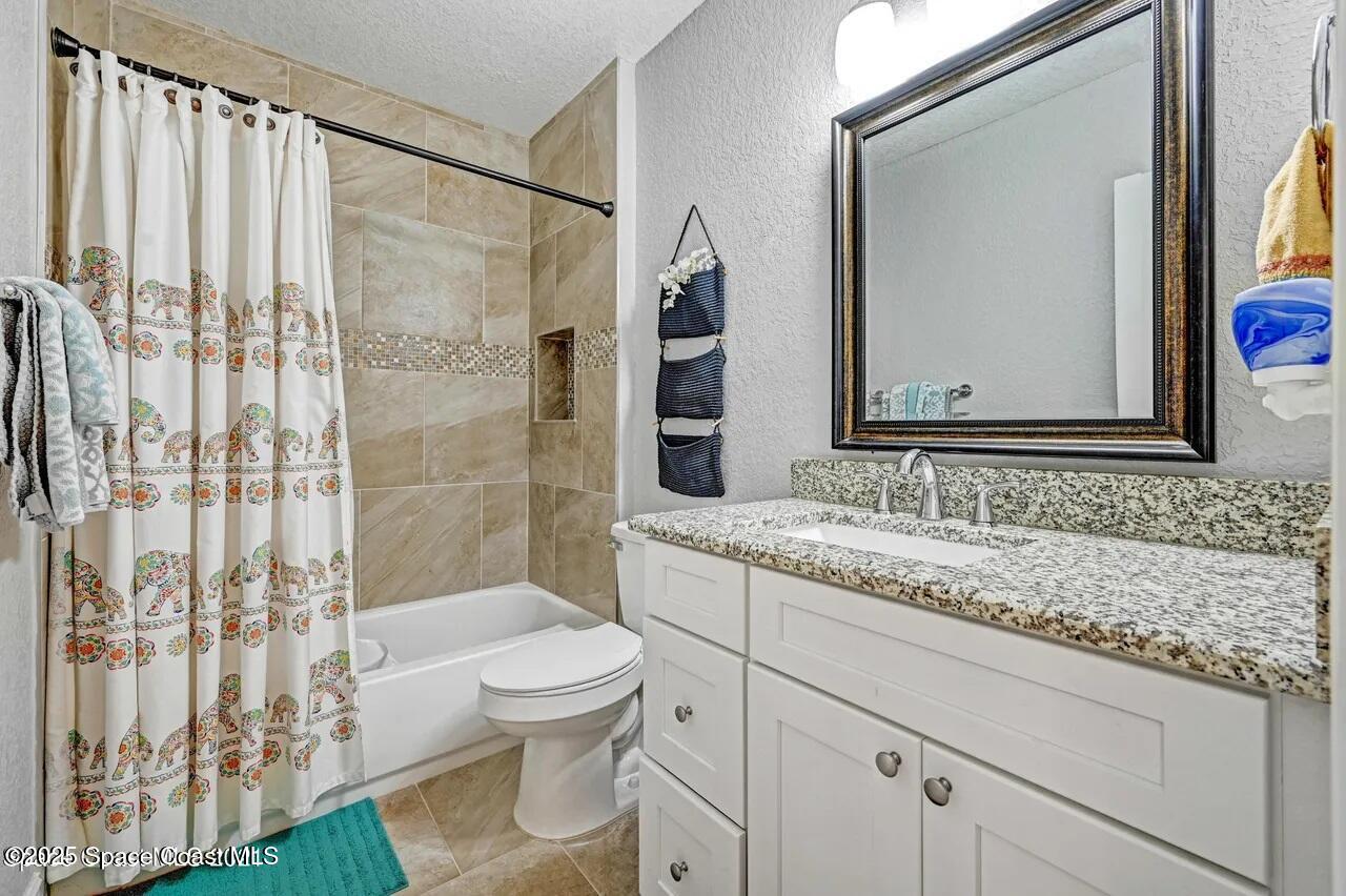 827 Glenmore Circle Melbourne, FL 32901 - Photo 14 of 30 a bathroom with a granite countertop sink a toilet and a mirror