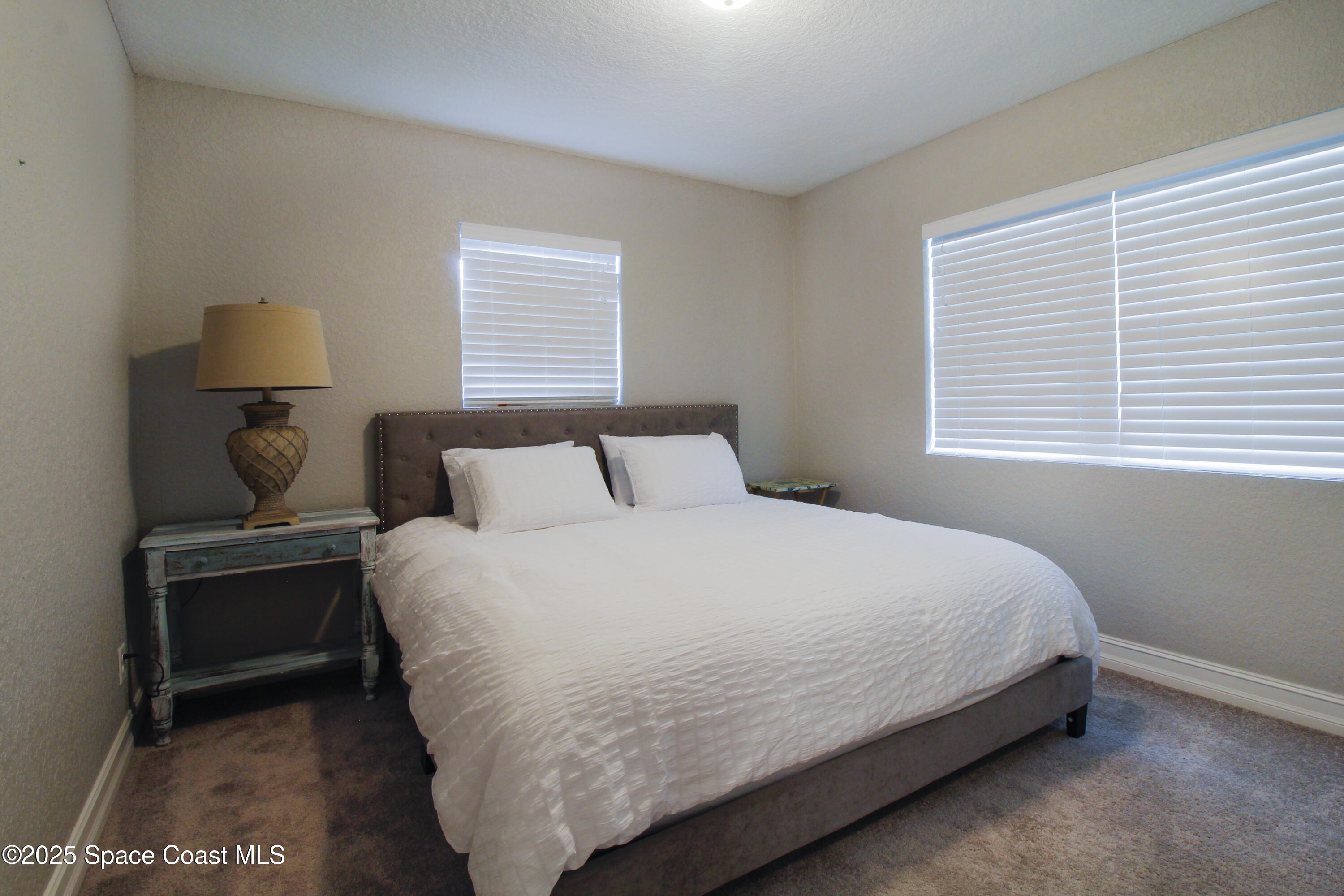 827 Glenmore Circle Melbourne, FL 32901 - Photo 15 of 30 a bedroom with a bed and a lamp on table