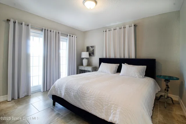 a large bed sitting in a bedroom next to a window and a chair