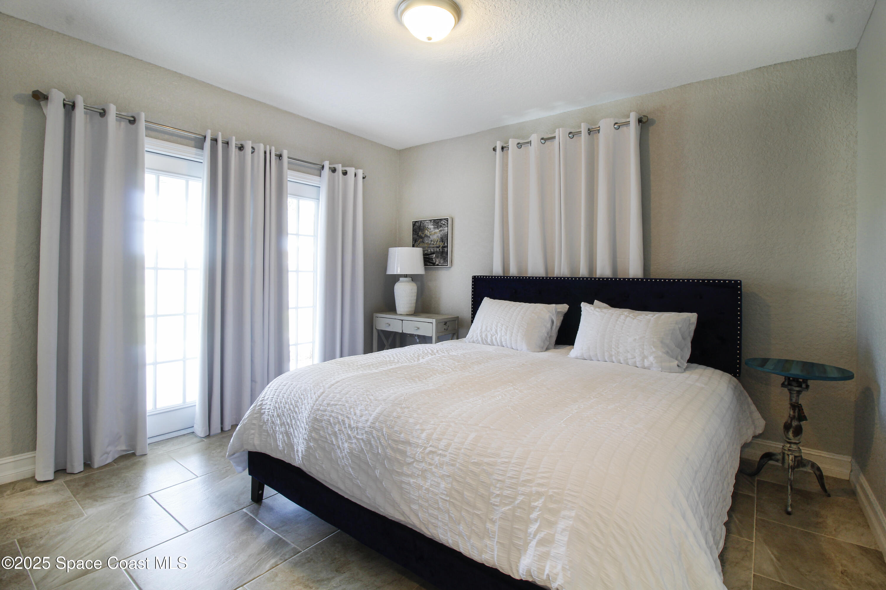 827 Glenmore Circle Melbourne, FL 32901 - Photo 19 of 30 a large bed sitting in a bedroom next to a window and a chair