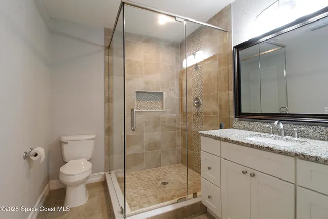 a bathroom with a granite countertop sink a toilet and shower