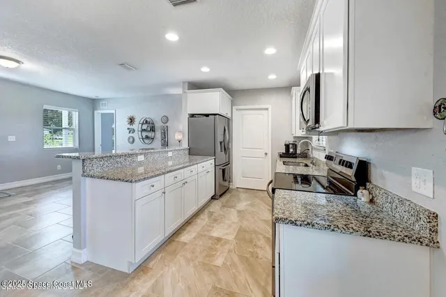 a kitchen with granite countertop kitchen island stainless steel appliances a sink stove and cabinets