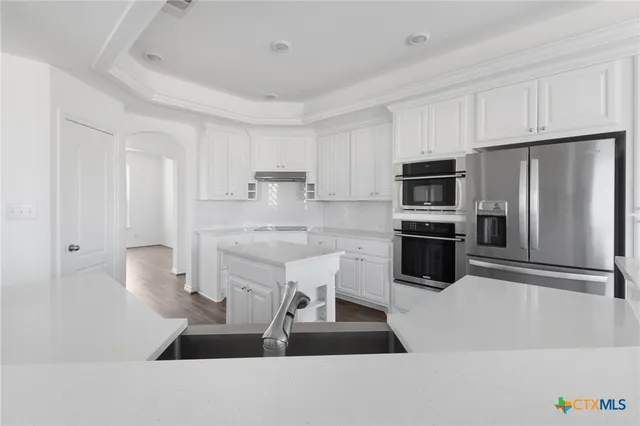 a kitchen with stainless steel appliances a refrigerator sink and white cabinets