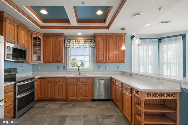 a kitchen with stainless steel appliances granite countertop a refrigerator a stove and a sink with large window