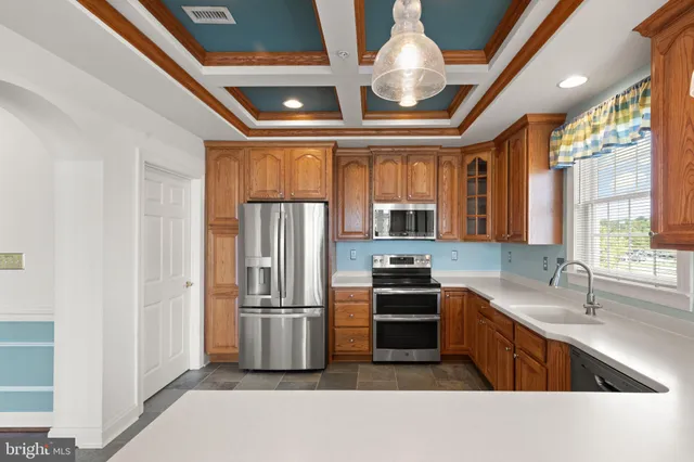 a kitchen with stainless steel appliances granite countertop a refrigerator oven a sink dishwasher and white cabinets with wooden floor