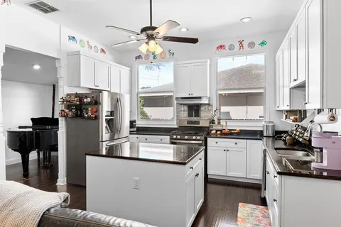 a kitchen with stainless steel appliances granite countertop a refrigerator a sink dishwasher a stove and white countertops with wooden floor