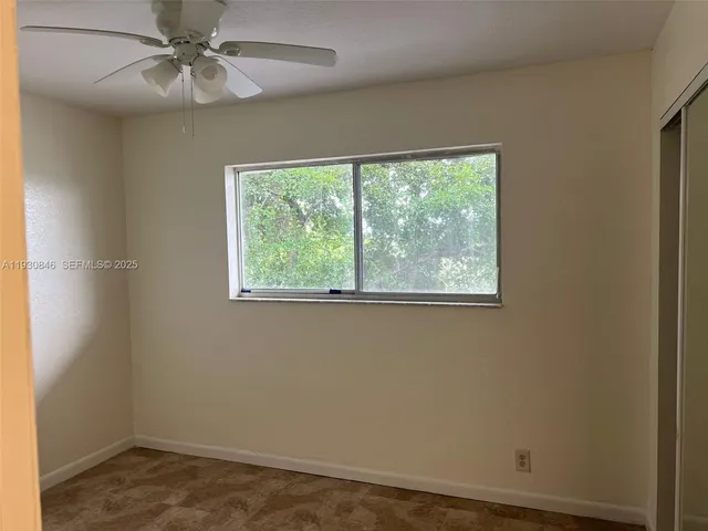 an empty room with a window and a fan