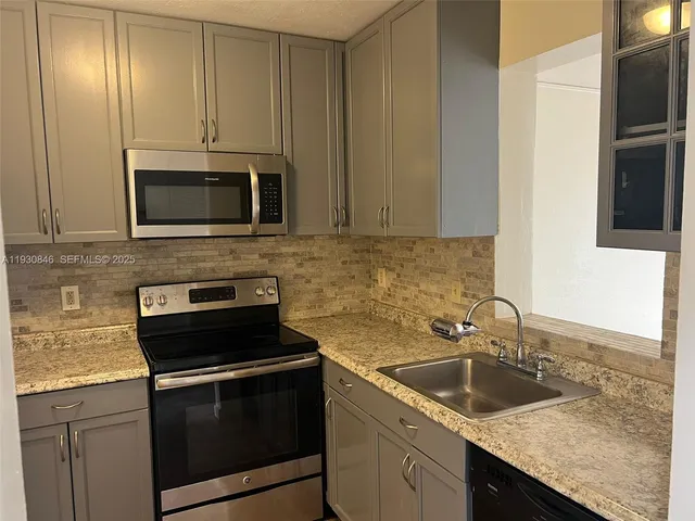 a kitchen with granite countertop white cabinets and stainless steel appliances