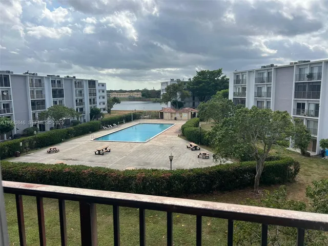 a view of a white house in front of a yard with potted plants