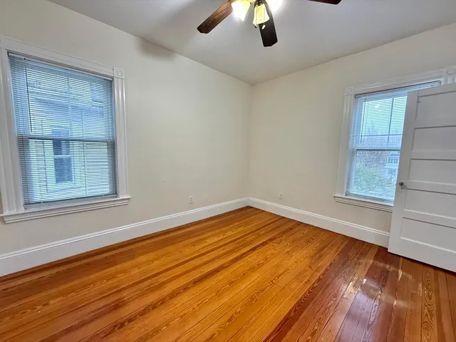a view of empty room with wooden floor and fan