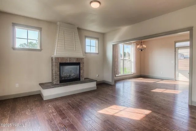 an empty room with wooden floor fireplace and windows