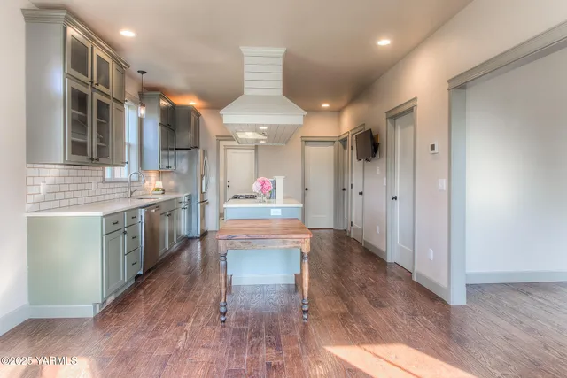 a large kitchen with a lot of counter space and wooden floor