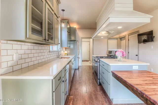a large kitchen with kitchen island a sink appliances counter top space and wooden floor