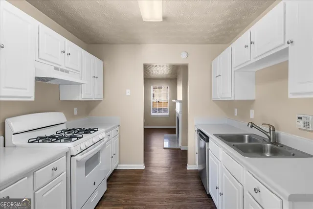 a kitchen with granite countertop a sink stove and refrigerator