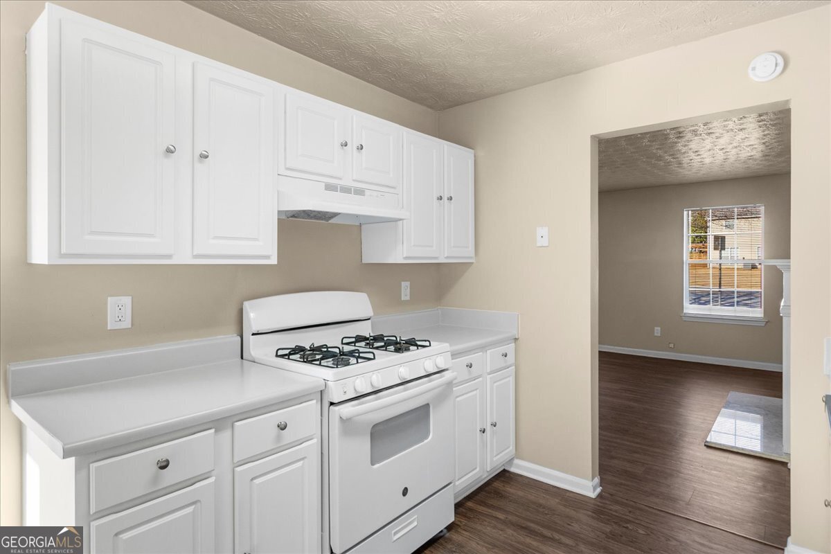 2603 Old Rex Morrow Road Ellenwood, GA 30294 - Photo 14 of 32 a kitchen with granite countertop a stove and a white cabinets