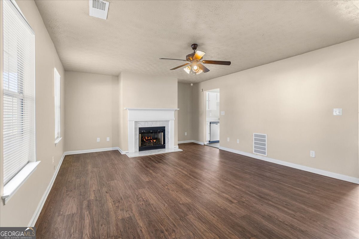 2603 Old Rex Morrow Road Ellenwood, GA 30294 - Photo 8 of 32 an empty room with wooden floor a ceiling fan a fireplace and windows