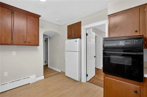 a view of a refrigerator in kitchen and an empty room