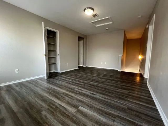 a view of an empty room with wooden floor and closet
