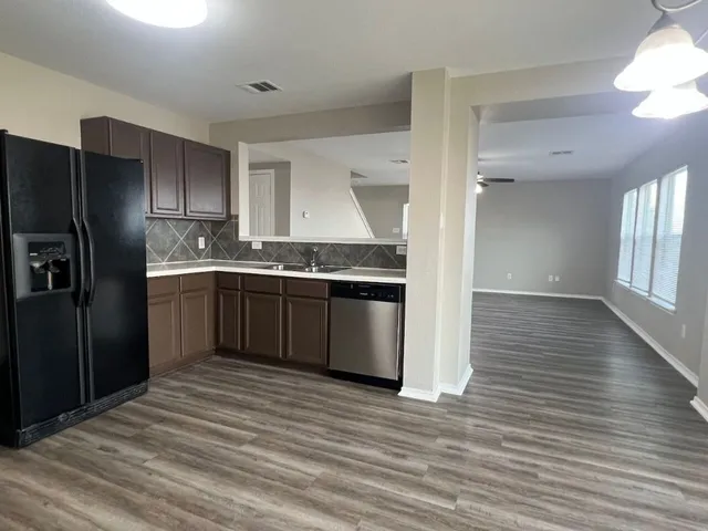 a kitchen with stainless steel appliances granite countertop a refrigerator a sink dishwasher a stove and a refrigerator