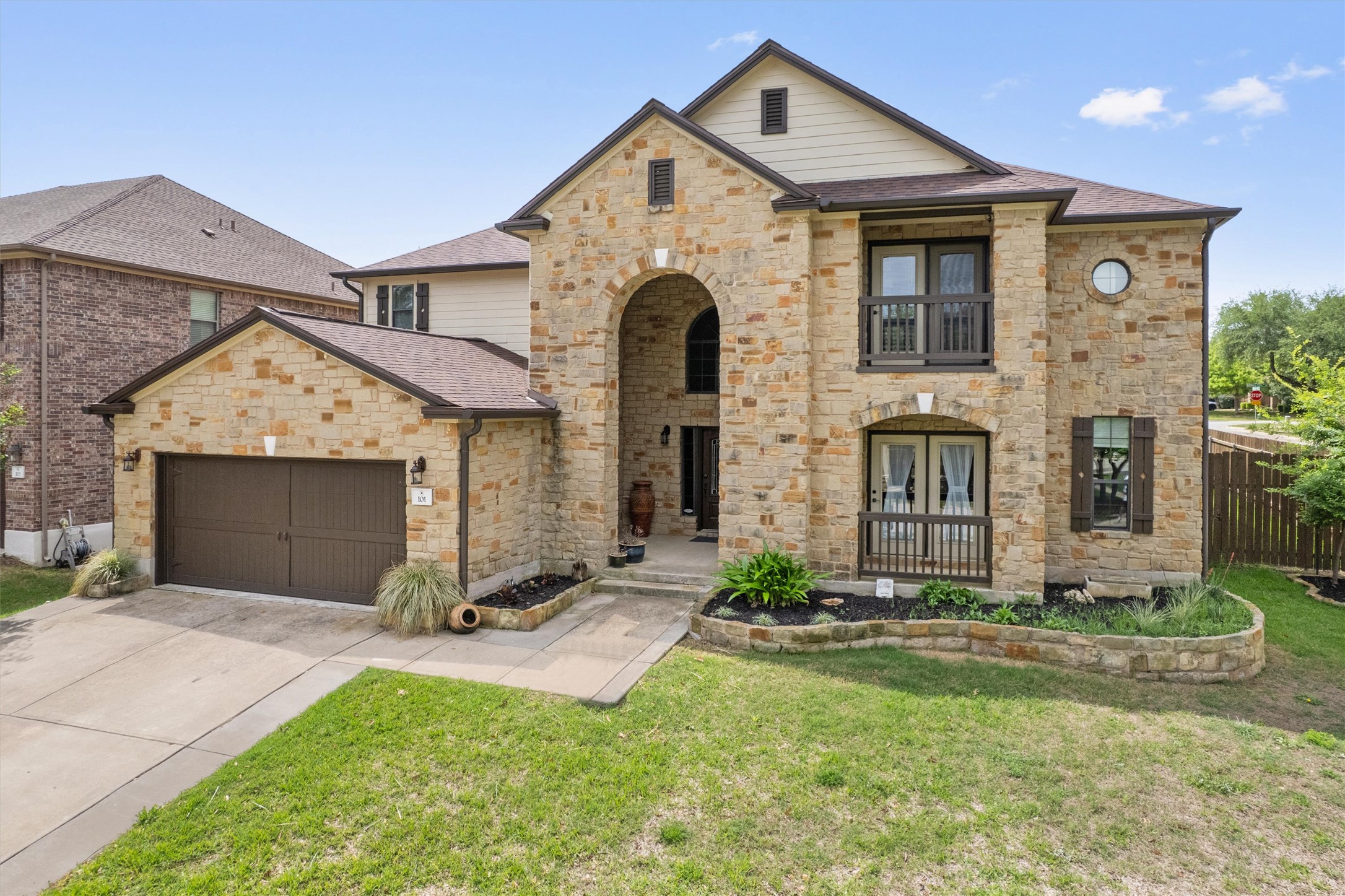 View of front of home with stone siding, driveway, and roof with shingles