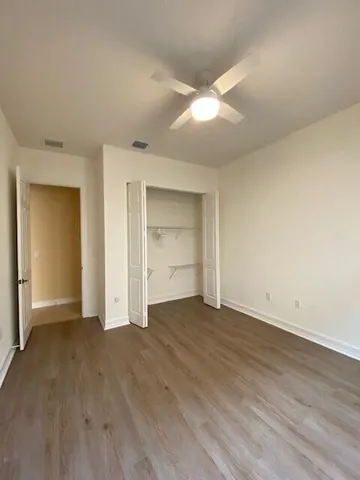 an empty room with wooden floor and windows with curtains