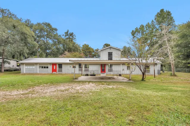 a view of a house with a big yard and large trees