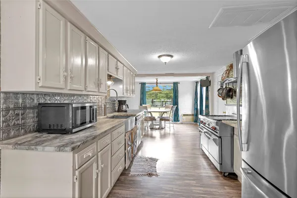 a kitchen with stainless steel appliances granite countertop a refrigerator a stove top oven a sink dishwasher and wooden cabinets with wooden floor