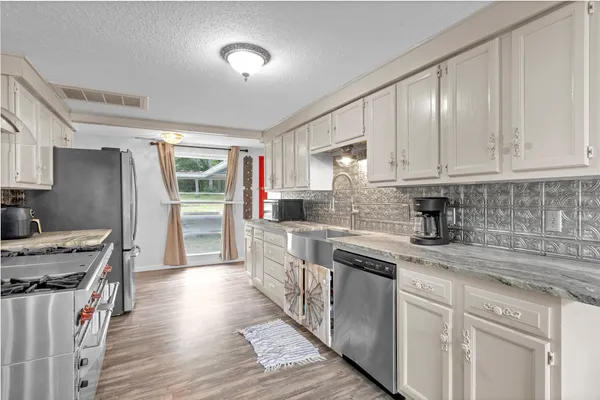 a kitchen with stainless steel appliances granite countertop a stove a sink dishwasher and a refrigerator